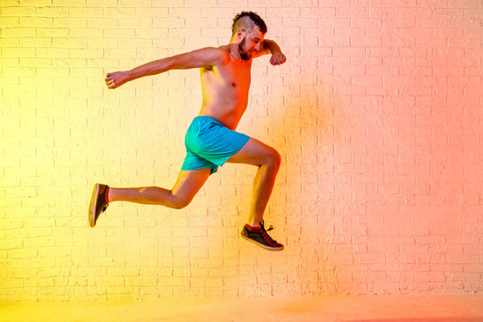 Young sporty man performs a jump on a yellow background. © mihakonceptcorn