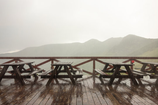 Empty benches in a cloud-burst in mountains with fog
