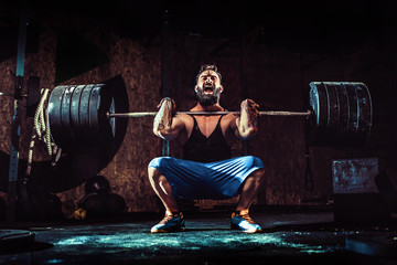 Muscular bearded tattoed fitness man doing deadlift a barbell over his head in modern fitness center. Functional training. Snatch exercise - obrazy, fototapety, plakaty
