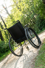 Fototapeta na wymiar Empty wheelchair parked in park, health care concept