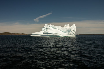 Large Iceberg floating through 'iceberg alley' off the coast of Newfoundland. Dark blue sky and water. 
