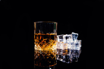whiskey with ice cubes on black background