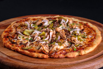 Gluten Free BBQ Chicken Pizza with lots of vegetable fillings, pickles and meat slices on a wooden board.