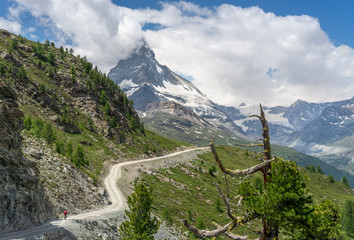 active senior woman, riding her electric mountainbike below the famous Matterhorn in Zermatt,...