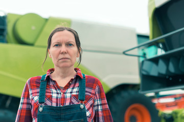 Female farmer posing in front of combine harvester