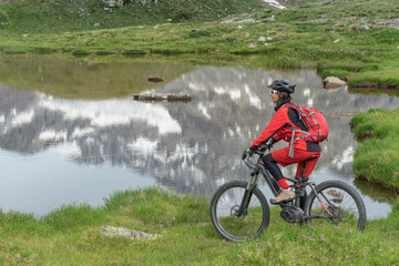 nice senior Woman riding her electric mountain bike at the Black Lake below Mount Matterhorn, Zermatt, Valais,Wallis,Switzerland, in the background Obergabelhorn and Zinalrothorn