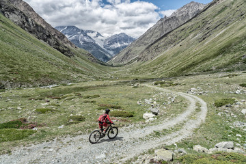 nice and ever young senior woman riding her electric mountainbike up to the Taeschalp, near Zermatt, Cantone Valais, Wallis, Switzerland