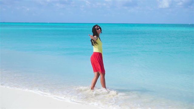 Beautiful young woman at beach walking in shallow water. Slow motion video.