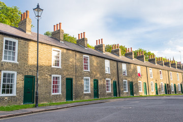 Row of restored Victorian brick houses with green colored doors and white windows.