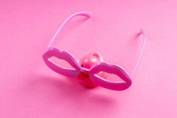Obraz na płótnie Canvas Pink funky rubber duck wearing lip shape glasses on neon monochrome. Pop art item composition.