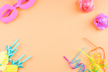Party cocktail straws and rubber ducks, funny glasses. Flat lay on orange pink background. Copy space frame