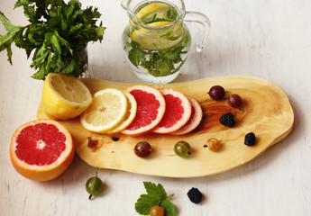 Fototapeta na wymiar lemonade in pitcher, sliced lemon and grapefruit ,fresh berries and a bundle of fresh mint on a white background /a healthy lifestyle