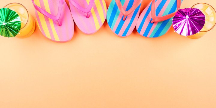 Vacation on the beach concept with colorful summer cocktails and flip flops on cantaloupe orange background. Copy space