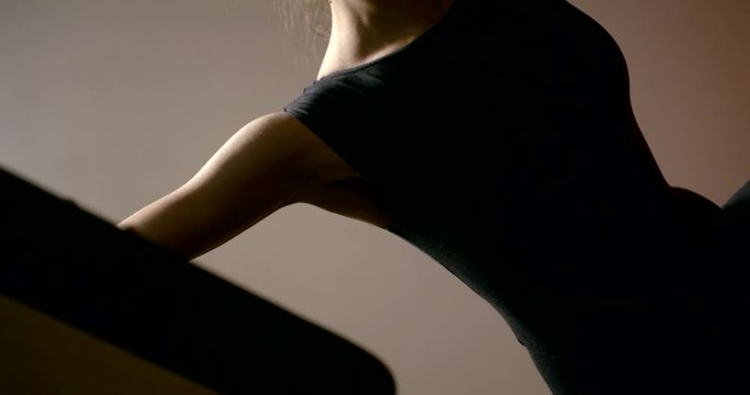 Close-up of the body of a sports girl, she is engaged in Pilates, doing exercises on the side bar with the help of a simulator.