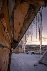 Icicles on the roof of wooden hut