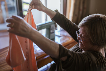 Senior woman holding a piece of clothing at home