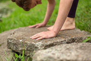 Thin brunette girl plays sports and performs yoga poses in a summer park. Green forest on the...
