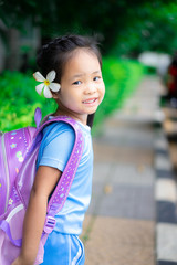 cute little girl with backpack walking in the park ready back to school