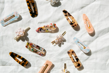 Group of Acrylic and Pearl Hair Clips on White Linen Background, Direct Sunlight, Women's Modern...