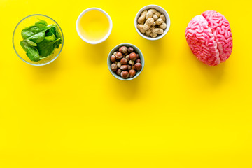 Energy food for brain work with peanut, hazelnut, seed-oil, spinage on yellow background top view space for text