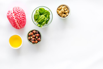 Energy food for brain work with peanut, hazelnut, seed-oil, spinage on white background top view space for text