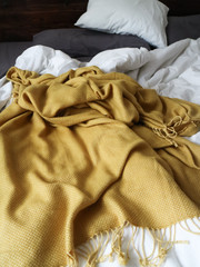 Yellow blanket in a cozy bed with white and grey pillows