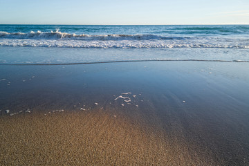 Detalle de las olas del mar retirándose de  la arena de la playa
