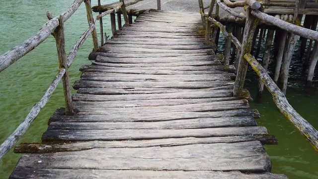 4K video of Old wooden footbridge over water. The camera goes slowly across the bridge. Below it is the clear waters of Lake Constance.
