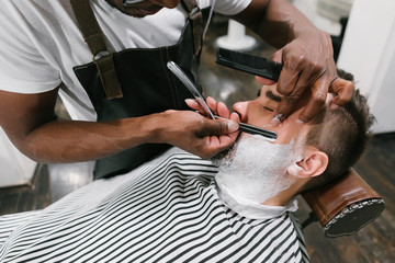 Man getting his beard shaved with razor in barber shop