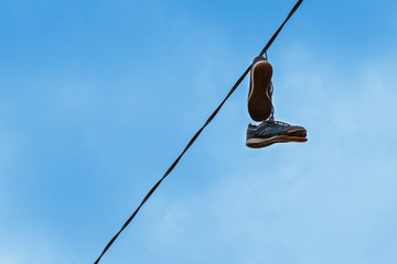 Old shoes with tied shoelaces hang on the wire