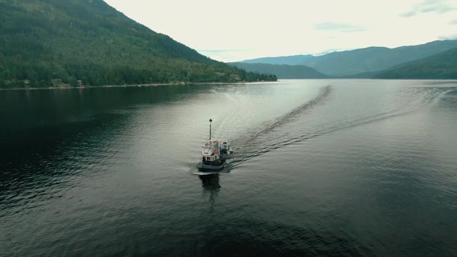 Aerial Drone Shot of Canadian Logging Tug Boat Pulling Logs & Timber Through Shuswap Lake, British Columbia, Canada. Logging Industry Forestry 