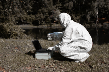 Ecological problem. Pollution. Examine oxygen. Scientist in protective mask and suit taking water...