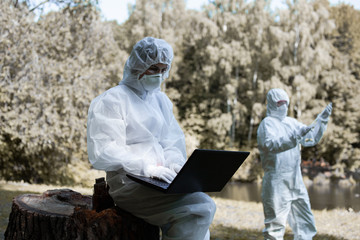 Ecological problem. Pollution. Examine oxygen. Scientist in protective mask and suit taking water samples from river. Chemist makes an analysis of the environment for radiation. 