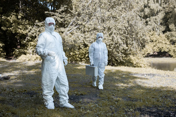 Fototapeta na wymiar Ecological problem. Pollution. Examine oxygen. Scientist in protective mask and suit taking water samples from river. Chemist makes an analysis of the environment for radiation. 