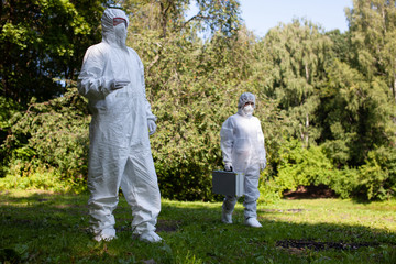 Ecological problem. Pollution. Examine oxygen. Scientist in protective mask and suit taking water samples from river. Chemist makes an analysis of the environment for radiation. 