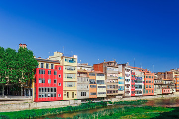 Colorful red, orange and yellow houses and bridge through river Onyar in Girona, Catalonia, Spain. Scenic ancient town. Famous tourist resort destination perfect place for holiday and vacation