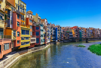 Colorful red, orange and yellow houses and bridge through river Onyar in Girona, Catalonia, Spain. Scenic ancient town. Famous tourist resort destination perfect place for holiday and vacation