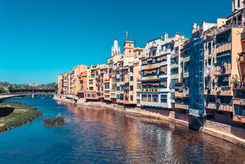 Colorful red, orange and yellow houses and bridge through river Onyar in Girona, Catalonia, Spain. Scenic ancient town. Famous tourist resort destination perfect place for holiday and vacation