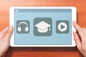 E-learning concept image. Closeup of hands touching white tablet computer on wooden desk. Application on screen. Front view image.