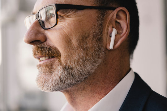 Portrait of mature businessman listening to music with  earbuds