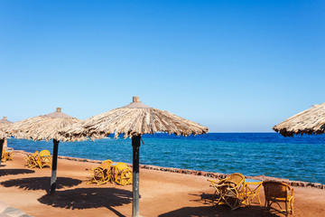 Sunny resort beach at the coast shore of Red Sea in Dahab, Sinai, Egypt, Asia in summer hot. Famous tourist destination near of Sharm el Sheikh. Bright sunny light