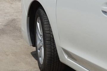 a gray passenger car with a black wheel stands on the asphalt road