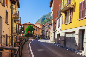Street near of beatiful Lake Como in Lombardy, Italy. Scenic small town with traditional houses and clear blue water. Summer tourist vacation on rich resort with harbour. Nice swans