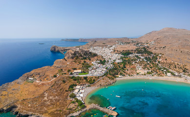 Obraz premium Aerial birds eye view drone photo of village Lindos, Rhodes island, Dodecanese, Greece. Sunset panorama with castle, Mediterranean sea coast. Famous tourist destination in South Europe.