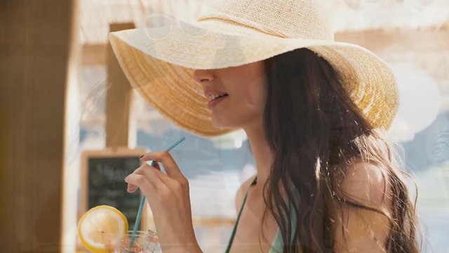 Young happy woman having a fresh drink at the beach bar