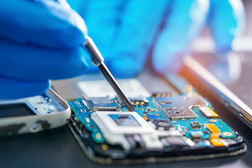 Asian Technician repairing micro circuit main board of smartphone electronic technology : computer,...