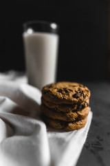 Cookies and a glass of milk with a dark textured background