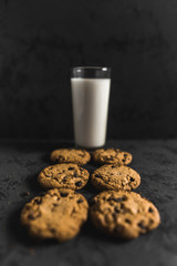 Cookies and a glass of milk with a dark textured background