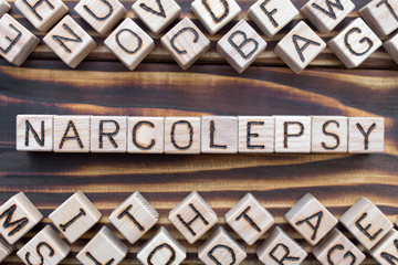 narcolepsy wooden cubes with letters, sleep disturbance  somnipathy concept, around the cubes random letters, top view on wooden background