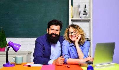 Two creative happy smiling students in auditorium. Happy casual girl student with bearded hipster teacher. University students at college. Students couple preparing for test or exam. School students.